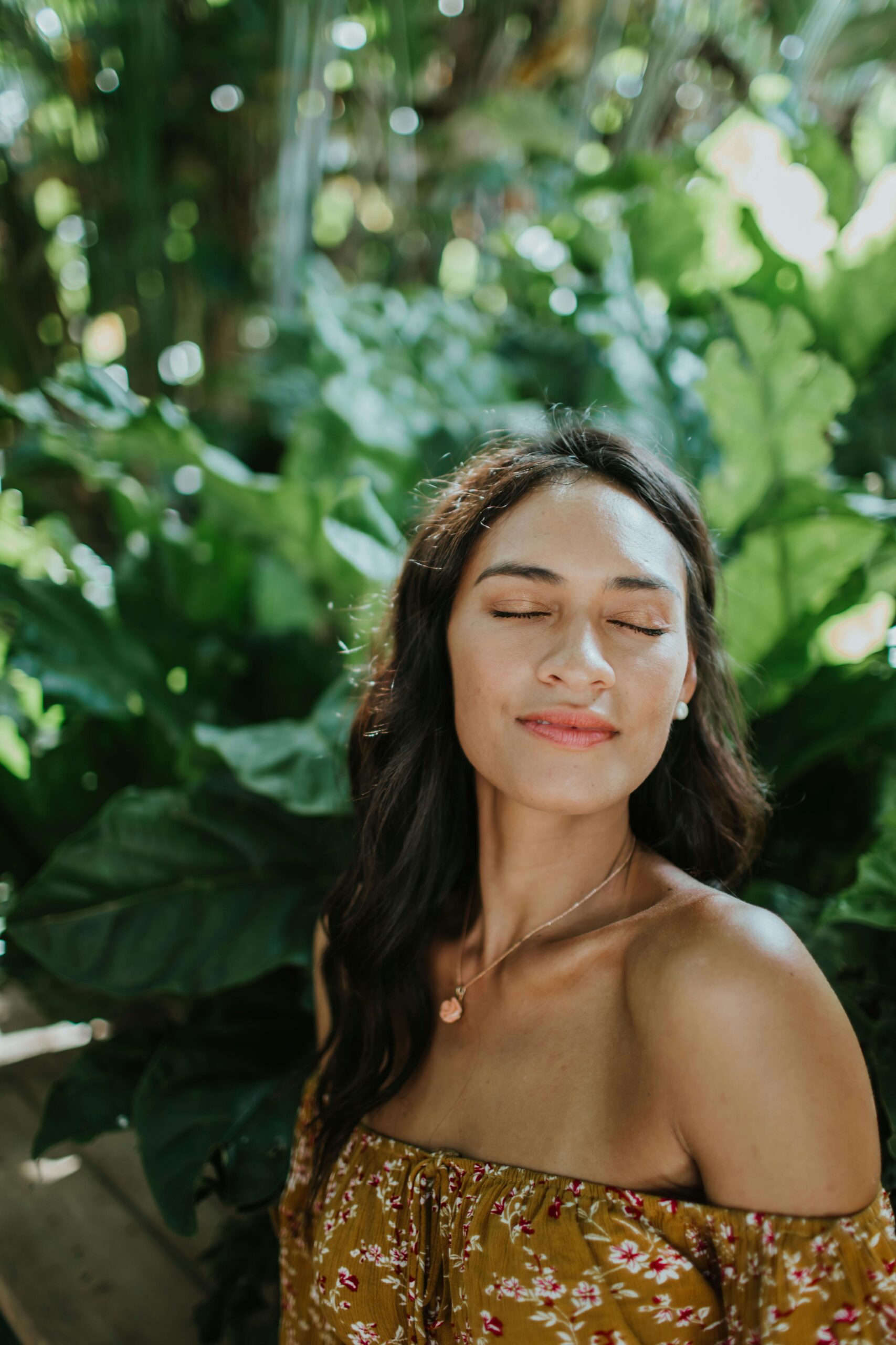 A serene woman with closed eyes savoring the sun amidst lush tropical greenery in Hawaii.